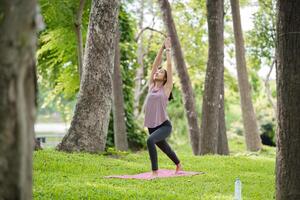 Woman Practicing Yoga in the Park, Relaxing and Meditating Outdoors in a Serene Natural Setting photo