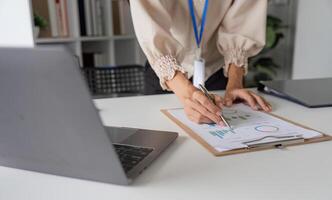 Close-up of Accountant Analyzing Financial Documents with Charts and Graphs in a Modern Office Setting photo