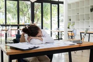 Exhausted Office Worker Sleeping at Desk with Laptop and Documents in Modern Workspace photo