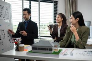 Business Team Discussing Real Estate Project with Architectural Plans and Model in Modern Office Setting photo