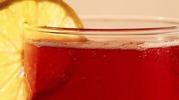 Closeup Shot Of Glass With Red Carbonated Drink And Lemon Slice And Bubbles Moving Up video