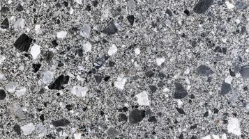 A black and white photo of a rocky surface with a few white specks.
