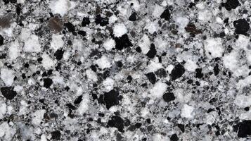 A close up of a stone wall with a grey and white color scheme. The stone is rough and jagged. photo