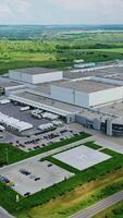 Huge territory of manufacturing in nature. Panoramic view of industrial plant in the middle of green fields. Aerial view. Vertical video