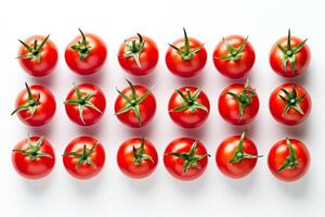 Many red tomatoes with green leaves forming a pattern on white background photo