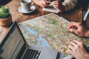 Digital nomads planning their next journey using a map and laptop photo