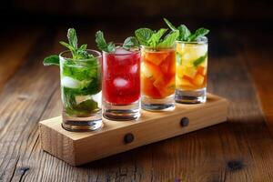 Four colorful cocktails with ice and mint on wooden table photo