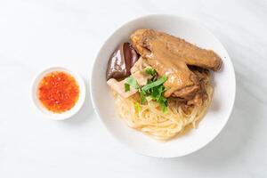 dried noodles with braised duck in white bowl photo