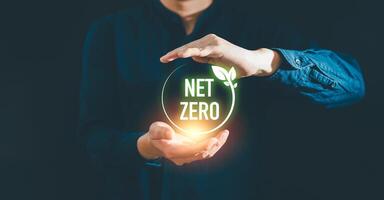 Businessman holding net zero icon with globe outline background for Net zero and carbon neutral concept. Net zero greenhouse gas emissions target. Climate neutral long term strategy. photo