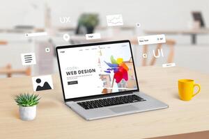 Laptop on a workspace displaying a web design studio webpage, with graphic web modules and elements floating around, illustrating the concept of dynamic website creation and design integration photo