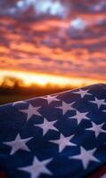 Close-up of American flag fabric with stars and stripes, vertical composition, sunset sky in the background photo
