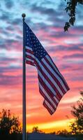 Vertical view of the American flag with fabric texture, colorful sunset sky in the background photo