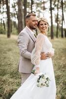 Wedding couple bride and groom walk hand in hand through a pine forest, sunlight filtering through the trees, highlighting their joyful expressions. photo
