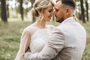 Wedding couple bride and groom walk hand in hand through a pine forest, sunlight filtering through the trees, highlighting their joyful expressions. photo
