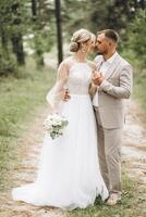 A bride and groom walk hand in hand through a pine forest, sunlight filtering through the trees, highlighting their joyful expressions. photo
