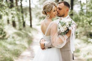 A bride and groom walk hand in hand through a pine forest, sunlight filtering through the trees, highlighting their joyful expressions. photo