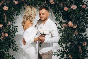 Romantic Wedding Portrait of a Couple Embracing in Front of Lush Greenery and Floral Backdrop photo
