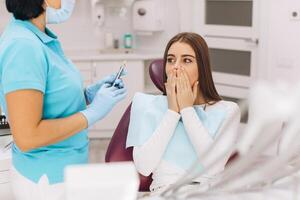 The dentist injects anesthesia to the girl patient, she is scared. photo