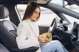 Young Woman Enjoying A Healthy Meal Inside Her Car During A Break From Work, Embracing A Busy Lifestyle While Maintaining Wellness Through Nutritious Eating Habits In A Modern Vehicle Setting photo