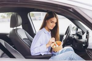 Young Woman Enjoying a Healthy Meal Inside Her Car, Emphasizing Modern Lifestyle Choices and Efficient Time Management, While Engaged in a Peaceful Break During a Busy Urban Day photo