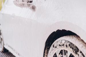 Close-Up of Car Covered in Soap Foam During Washing photo