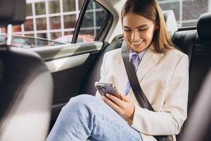 Smiling Woman Using Smartphone While Traveling in Car photo