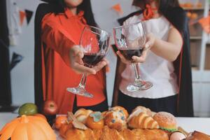friendship, holiday and people concept - group of happy smiling friends in halloween costumes of vampire, devil, witch and cheetah at home party photo