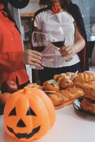 friendship, holiday and people concept - group of happy smiling friends in halloween costumes of vampire, devil, witch and cheetah at home party photo