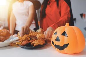 friendship, holiday and people concept - group of happy smiling friends in halloween costumes of vampire, devil, witch and cheetah at home party photo
