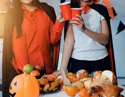 friendship, holiday and people concept - group of happy smiling friends in halloween costumes of vampire, devil, witch and cheetah at home party photo