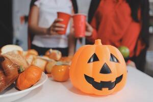 friendship, holiday and people concept - group of happy smiling friends in halloween costumes of vampire, devil, witch and cheetah at home party photo