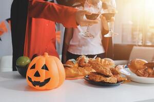 friendship, holiday and people concept - group of happy smiling friends in halloween costumes of vampire, devil, witch and cheetah at home party photo