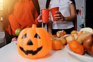 friendship, holiday and people concept - group of happy smiling friends in halloween costumes of vampire, devil, witch and cheetah at home party photo