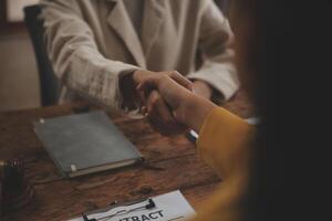 Lawyer shaking hands with a client making about documents, contracts, agreements, cooperation agreements with a female client at the lawyer's desk and a hammer at the table. photo