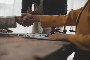 Lawyer shaking hands with a client making about documents, contracts, agreements, cooperation agreements with a female client at the lawyer's desk and a hammer at the table. photo