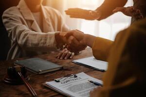 Lawyer shaking hands with a client making about documents, contracts, agreements, cooperation agreements with a female client at the lawyer's desk and a hammer at the table. photo