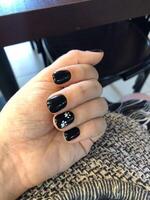 Close-up of a hand with black nail polish and white paw print nail art. photo