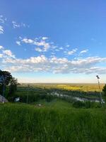 Scenic view of lush landscape with river and vast sky and the ski lift not work in summer. Panorama of nature captured from hilltop during serene summer day. photo