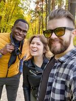 Three friends enjoy a sunny day in the forest, capturing moments and smiles. Selfie and diversity concept photo