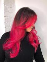 Close-up of the wavy pink hair of a young woman isolated on a gray background. Result of coloring, highlighting, perming. Beauty and fashion photo