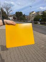 Close up male hand holds yellow envelope in urban city background. Mail, parcels and packages concept. photo