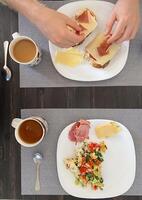 acogedor desayuno ajuste muestra un persona preparando abierto enfrentó emparedados mientras otro plato muestra un vistoso lucha con café tazas cercano. retrata un hogareño y atractivo Mañana comida foto