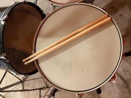 Pair of wooden drumsticks rests on a snare drum, inviting rhythm and energy. Musical experience waiting to unfold in this intimate setting photo