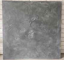 Textured gray canvas leans against a white brick wall, offering a stark contrast and highlighting the intricate details within the artwork. Artistic blend of the canvas photo