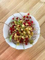 Delightful mix of red and white currants fills a white bowl, capturing the essence of summer freshness. Rustic wooden background enhances the natural, inviting presentation of the berries photo