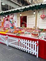 Colorful heart-shaped cookies hang elegantly on display at a festive Christmas market stall. Vibrant array of sweets. Inviting and cheerful atmosphere winter holidays. photo