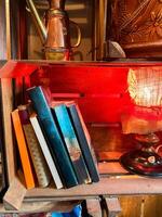 Collection of colorful books rests on a wooden shelf next to warm, glowing lamp. Cozy, inviting atmosphere perfect for reading and relaxation photo