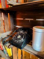Vintage rotary phone sits on a rustic wooden shelf, accompanied by a simple metal tin. this image captures a sense of nostalgia and timeless charm, evoking memories of past eras photo