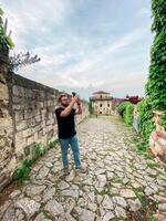 A man takes a photo while standing at a viewpoint in fortress. A tourist with a smartphone camera