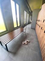 Wooden bench in empty locker room at gym photo